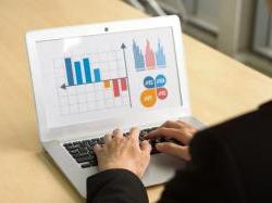 企业主面对桌上的笔记本电脑，显示图表和统计数据